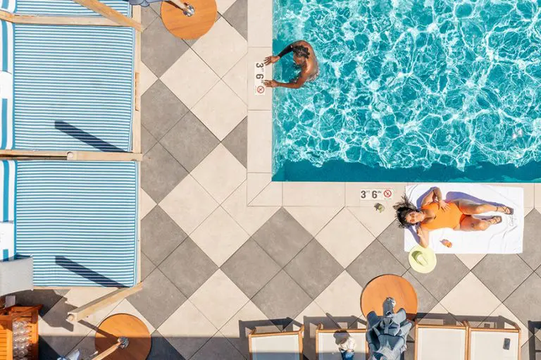 Aerial view of a Cherry Creek North pool with people swimming and sunbathing on a sunny day.