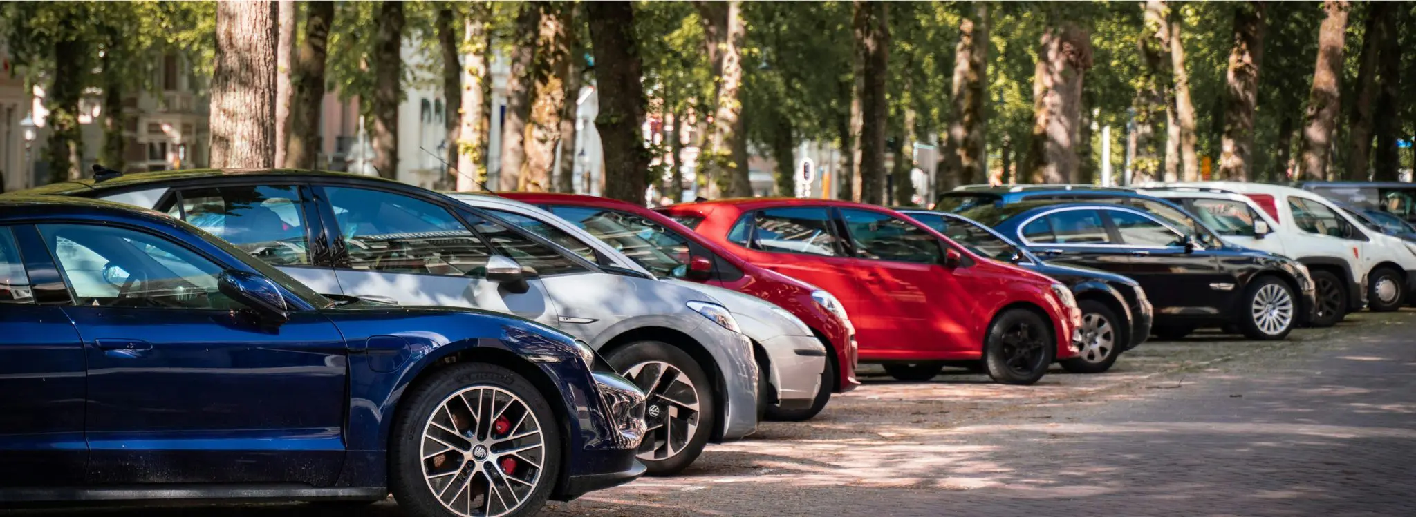 Cars parked in a row along a tree-lined street, a parking option.