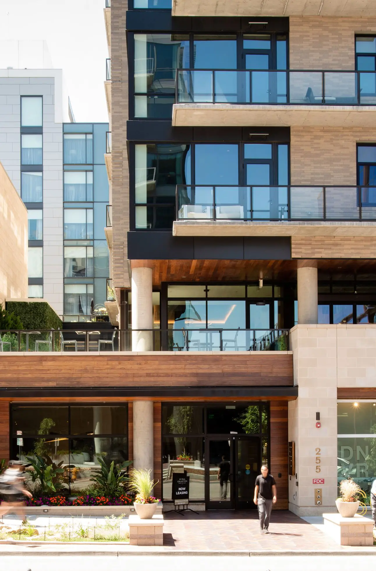 Modern apartment building with leasing sign and street view.