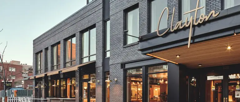 The Clayton building with a sleek brick facade and modern design. "Clayton" signage is visible.