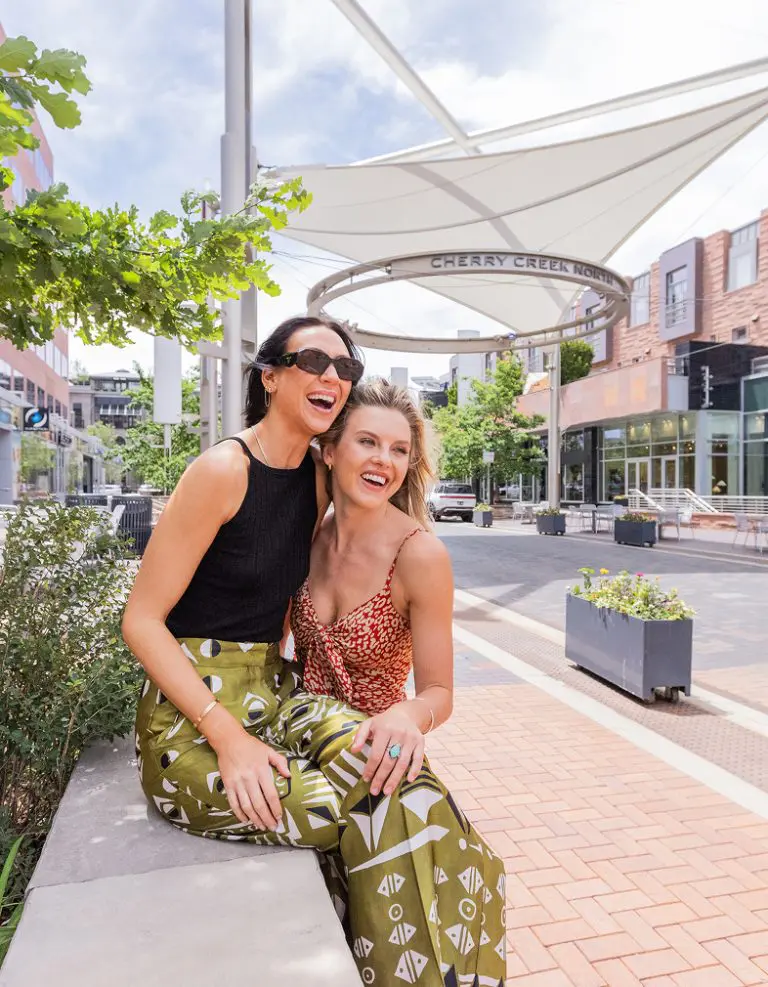 Two stylish women laugh in Cherry Creek North, Denver.