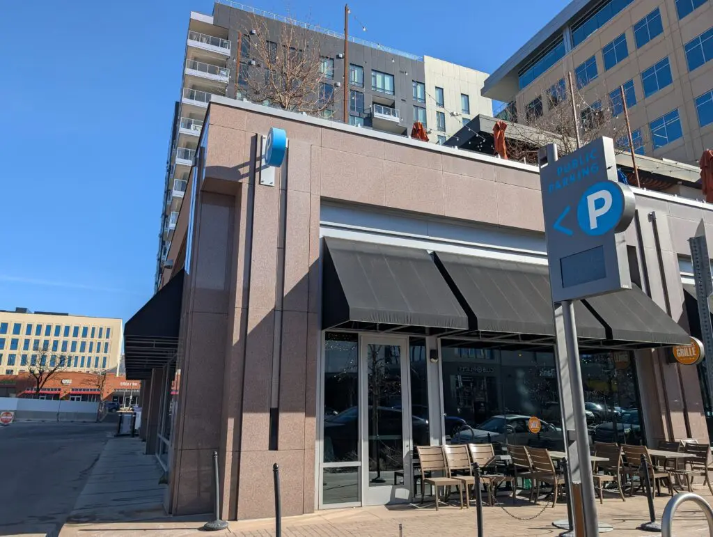 Outdoor seating area at 100 Saint Paul Garage with a "Public Parking" sign.