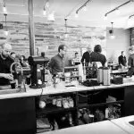 Busy baristas at Aviano Coffee prepare drinks for customers, showcasing the cafe's atmosphere.