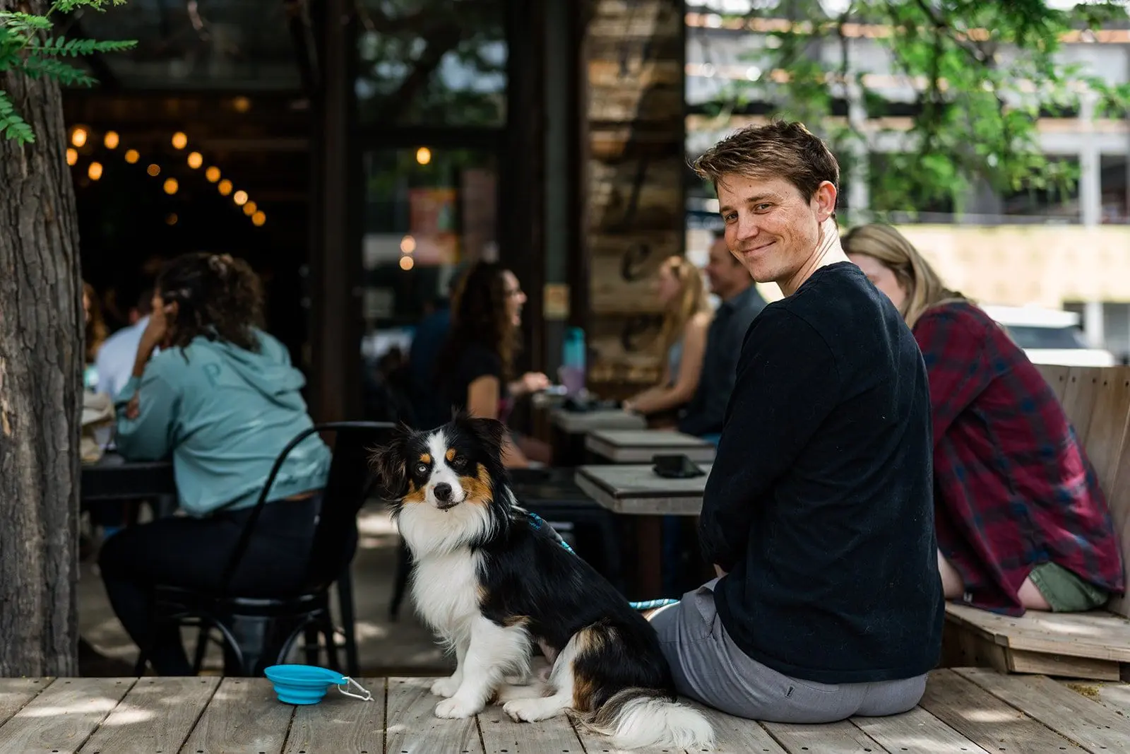Man with dog on a patio at an outdoor cafe.