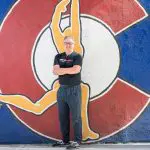 Kinetic Fitness Studio owner stands in front of Colorado flag mural.