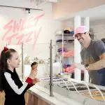 Girl receives ice cream at Sweet Izzy from a smiling employee.