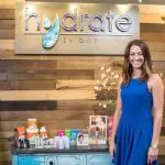 Woman at Hydrate IV Bar with products on display.