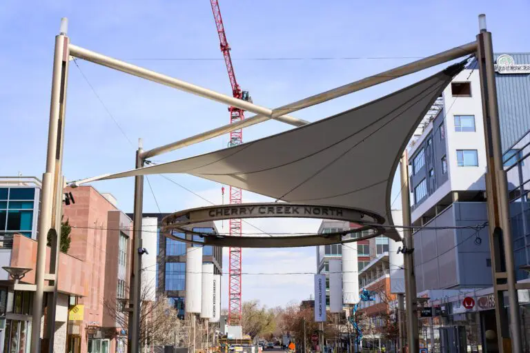 Cherry Creek North street view with modern architecture, construction crane, and overhead signage.