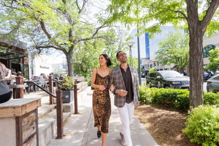 A man and woman walking arm in arm down a sidewalk