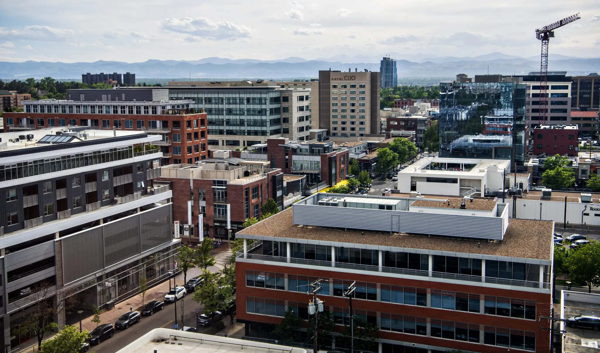 Denver skyline featuring Hotel Clio and the Rocky Mountains in the background.