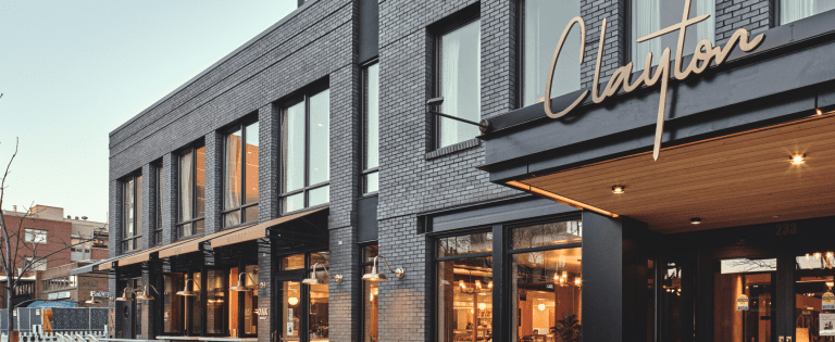 The Clayton Hotel exterior with modern black brick, large windows, and stylish signage.