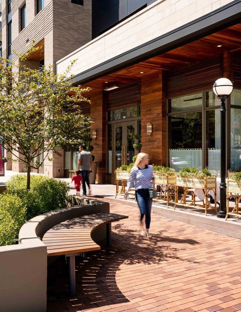 Person walking down a sidewalk next to a patio