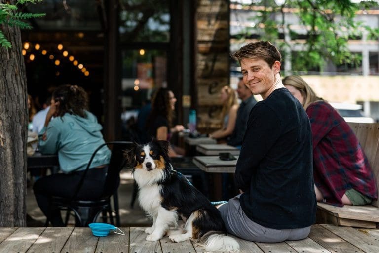 Man with dog on a patio at an outdoor cafe.