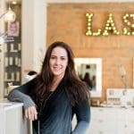 Live Love Lash salon owner standing in front of "LASH" sign.