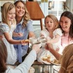 Mothers and daughters toasting tea cups at a Mother's Day celebration.