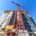 Cherry Creek construction site with a red crane and building facade under development.