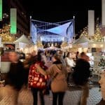Nighttime view of the Cherry Creek Holiday Market with vendor booths and shoppers.