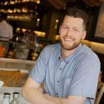 Man at Blue Island Seafood and Oyster Bar smiling in front of the bar area.