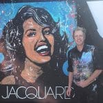 Artist stands next to a painting of a woman with "JACQUARD" text below.