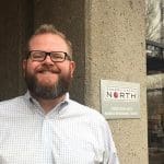 Brian Phetteplace stands in front of the Cherry Creek North Business Improvement District sign.
