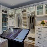 Elegant walk-in closet by California Closets featuring drawers, shelving, and glass-front cabinets.