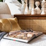 Stylish home office detail: cozy chair, throw, book, glasses, and decorative vases.