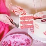 Pink cake with kiss mark decorations being served at a Valentine's Day Soirée.