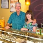 Enstrom Candies owners smiling behind a display case filled with chocolates.