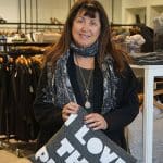 Woman in Garbarini boutique holding a pillow. Clothing racks in background.