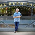 Man stands in front of The Hermitage Antiquarian Bookshop sign.