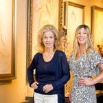 Two women stand in Masters Gallery, surrounded by artwork.