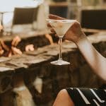 Woman enjoys a cocktail by a warm fire pit at JW Marriott, part of Social Fare.
