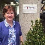 Susan Fry stands next to a Cherry Creek North sign.