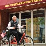 Man on trike with wine outside The Vineyard Wine Shop. est. 1971.