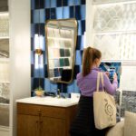 Woman taking photo of blue tile in bathroom design showroom.