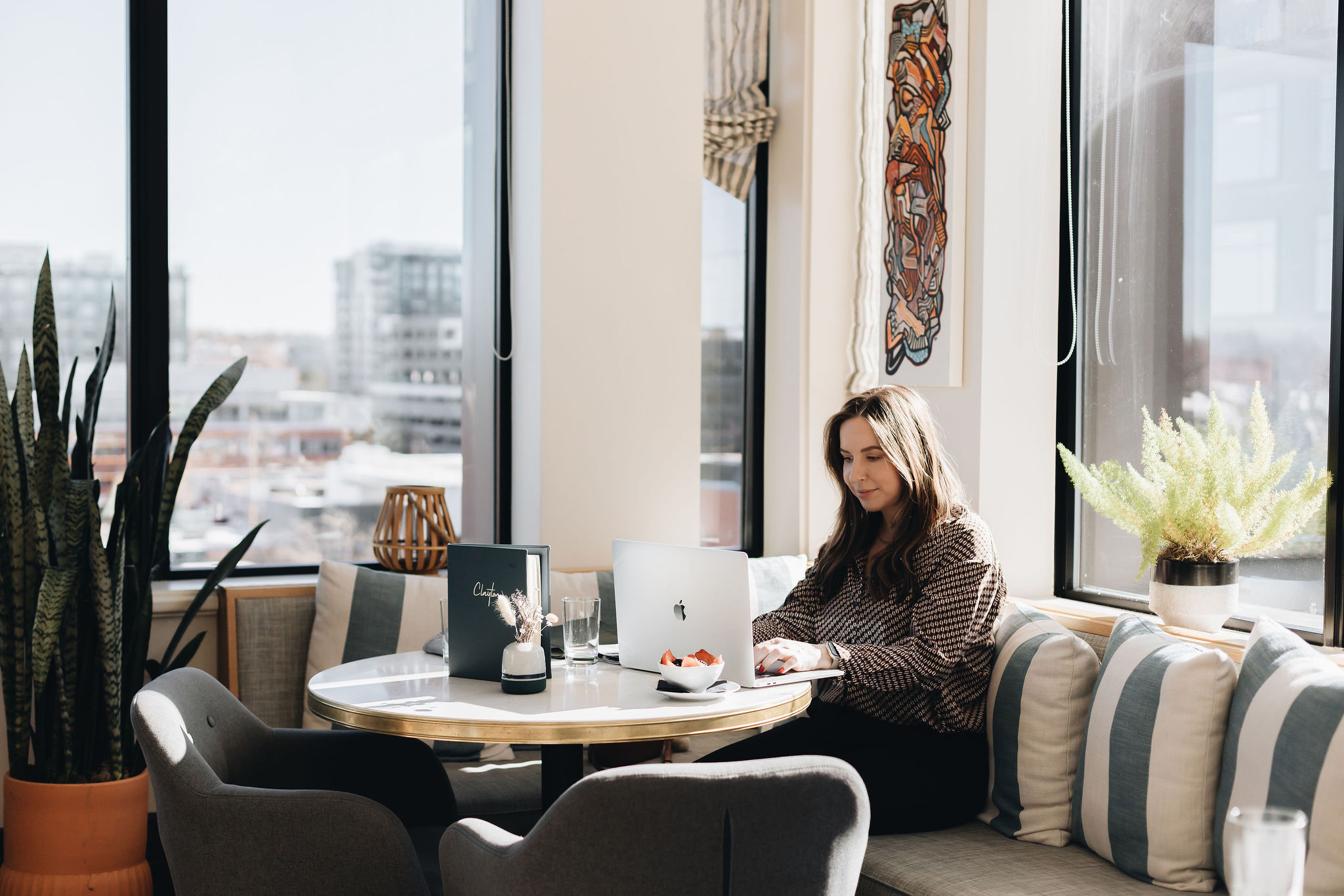 Woman working on laptop in bright, modern cafe with city view