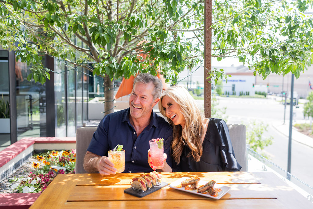 Couple enjoying cocktails and sushi at an outdoor patio restaurant
