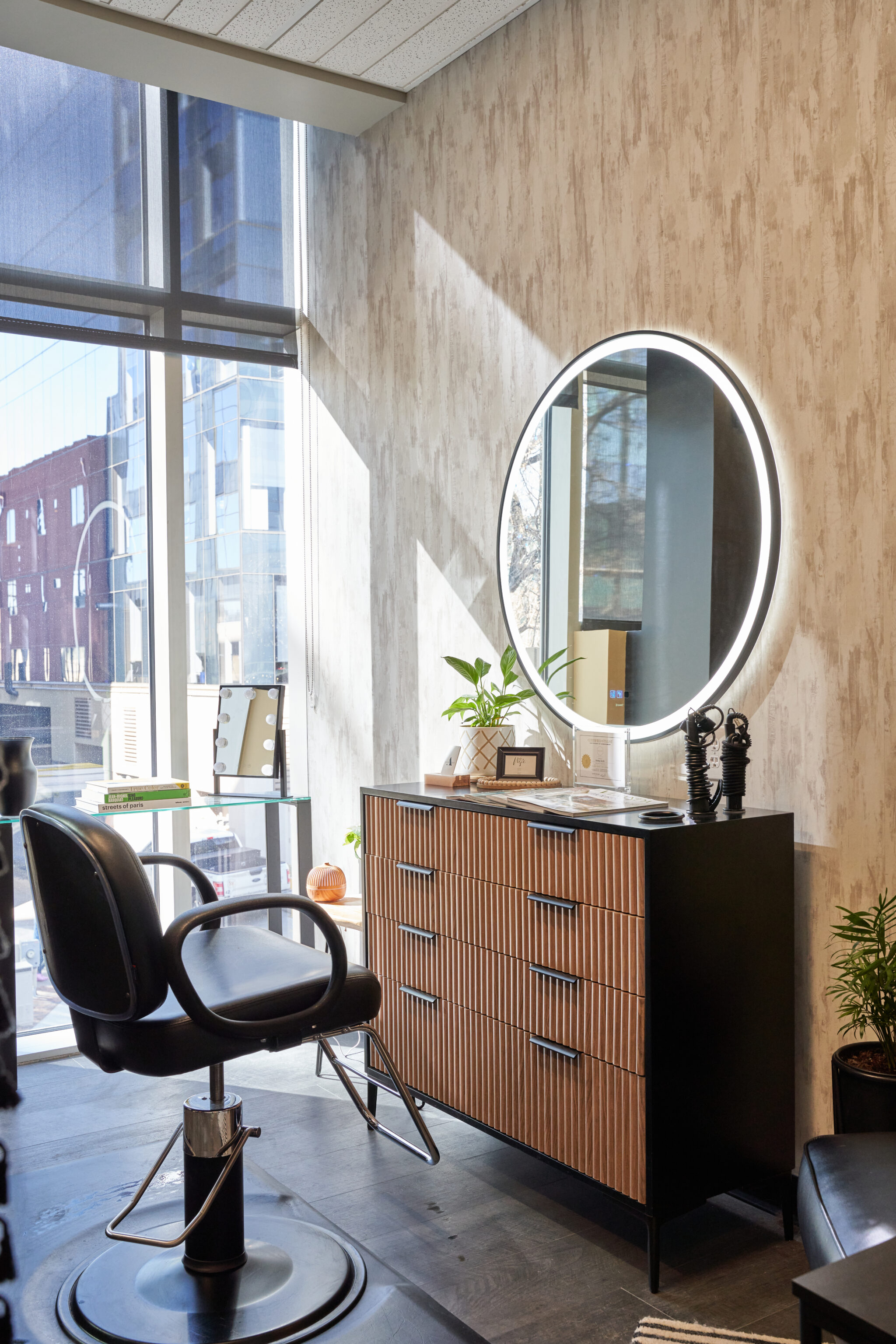 Black chair and brown wooden drawers with a plant on the side